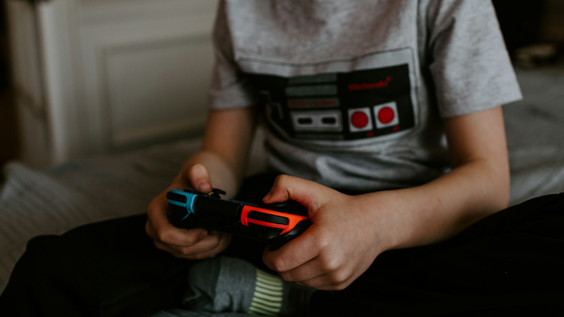 Gamer at a warmly lit setup surrounded by controllers and retro consoles